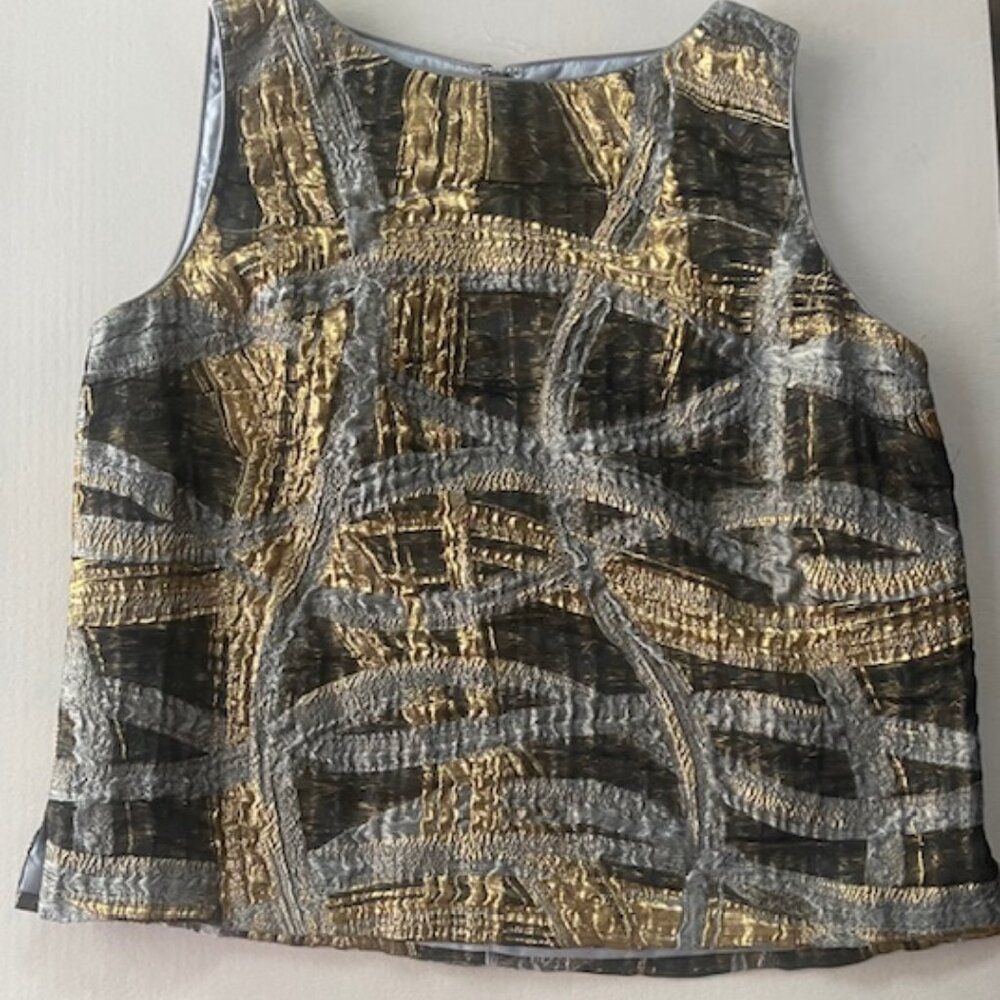 Sleeveless top features a textured, metallic fabric in gold, and silver